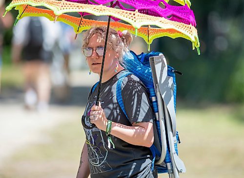 BROOK JONES / FREE PRESS
Folk Fest goer Liz Disenchanted, 30, who is from Winnipeg, Man., keeps cool on a hot summer day by using a giant sun umbrella as she attends the 49th Winnipeg Folk Festival at Birds Hill Provincial Park in Man., Sunday, July 14, 2024. Disenchanted has been attending Folk Fest since 2018.