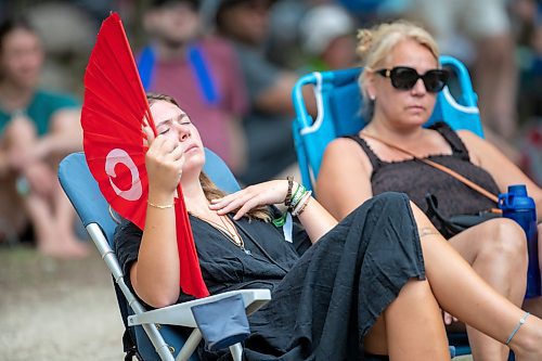 BROOK JONES / FREE PRESS
Folk Fest goer Grace Wallace, 22, who is from Lockport, Man., keeps cool on a hot summer day by waving a giant hand fan as she listens to Steph Strings, who is a musician based in Melbourne, Australia, perform on the Little Stage In The Forest at the 49th Winnipeg Folk Festival at Birds Hill Provincial Park in Man., Sunday, July 14, 2024. Wallace has been attending Folk Fest since she was three-months-old.