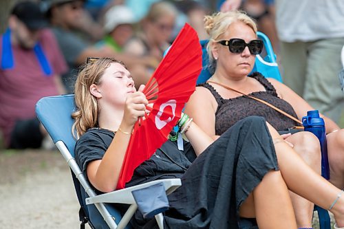 BROOK JONES / FREE PRESS
Folk Fest goer Grace Wallace, 22, who is from Lockport, Man., keeps cool on a hot summer day by waving a giant hand fan as she listens to Steph Strings, who is a musician based in Melbourne, Australia, perform on the Little Stage In The Forest at the 49th Winnipeg Folk Festival at Birds Hill Provincial Park in Man., Sunday, July 14, 2024. Wallace has been attending Folk Fest since she was three-months-old.