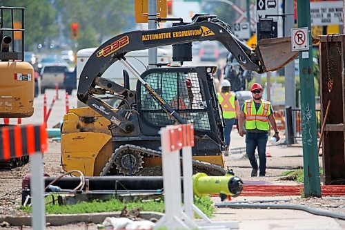 A construction worker on the west sidewalk along 18th Street at the intersection of Park Avenue is seen under the raised bucket of a compact track loader on Monday afternoon. (Matt Goerzen/The Brandon Sun)