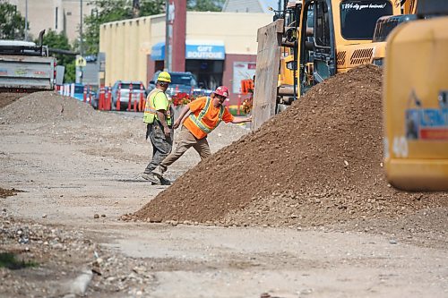 Construction crew members work to move a heavy piece of equipment on the southbound landes of 18th Street near the Park Avenue intersection on Monday afternoon. (Matt Goerzen/The Brandon Sun)