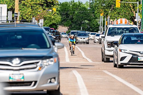 NIC ADAM / FREE PRESS
A cyclist rides past parked cars on St. Mary Ave., near Donald St., Wednesday.
240717 - Wednesday, July 17, 2024.

Reporter: Joyanne