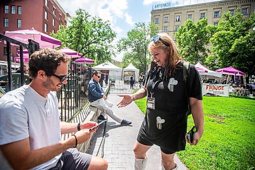 MIKAELA MACKENZIE / FREE PRESS

Kate Tobie (right) hands a pamphlet for her show, HerPlease, to Dale Kujanpaa as Fringe festival launches at Old Market Square on Wednesday, July 17, 2024.

