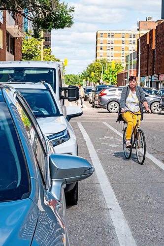 NIC ADAM / FREE PRESS
A cyclist rides past parked cars on St. Mary Ave., near Donald St., Wednesday.
240717 - Wednesday, July 17, 2024.

Reporter: Joyanne