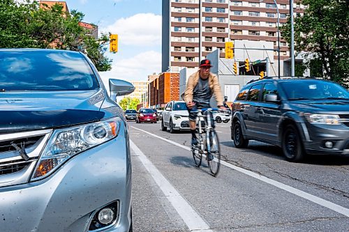 NIC ADAM / FREE PRESS
A cyclist rides past parked cars on St. Mary Ave., near Donald St., Wednesday.
240717 - Wednesday, July 17, 2024.

Reporter: Joyanne