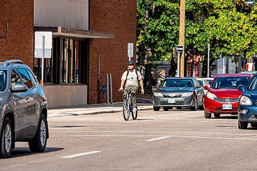 NIC ADAM / FREE PRESS
A cyclist rides past parked cars on St. Mary Ave., near Donald St., Wednesday.
240717 - Wednesday, July 17, 2024.

Reporter: Joyanne