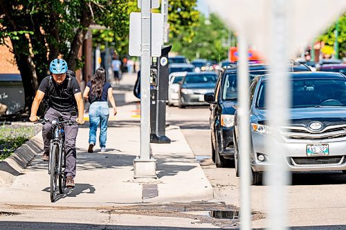 NIC ADAM / FREE PRESS
A cyclist rides past parked cars on St. Mary Ave., near Donald St., Wednesday.
240717 - Wednesday, July 17, 2024.

Reporter: Joyanne