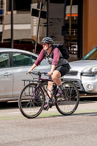 NIC ADAM / FREE PRESS
A cyclist rides past parked cars on St. Mary Ave., near Donald St., Wednesday.
240717 - Wednesday, July 17, 2024.

Reporter: Joyanne