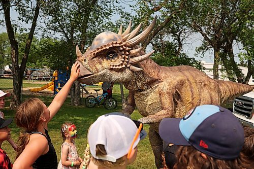 18072024
Kids interact with Stevie the Stygimoloch at the DinoMite Adventures booth during the Hamiota Agricultural Society Fair on a hot Thursday afternoon. The fair included a mini golf tournament, a Mario Kart tournament, beach volleyball and baseball, a movie night, livestock shows and a variety of other entertainment and activities.
(Tim Smith/The Brandon Sun)