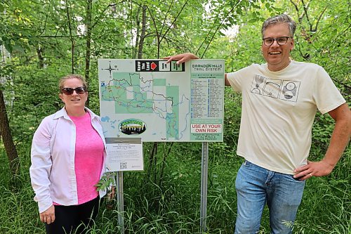 Brandon University associate professor of anthropology Emily Holland and marketing and communications director Grant Hamilton stand by one of the trail map display boards at the Brandon Hills Wildlife Management Area Trailhead on Friday. (Abiola Odutola/The Brandon Sun)