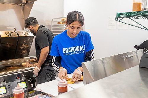 BROOK JONES / FREE PRESS
Boardwalk Fries Burgers Shakes at the Park West Shopping Centre located at 6650 Roblin Blvd. in Winnipeg, Man., is celebrating its grand opening Friday, July 19, 2024. Line cook Kiran Karur is pictured placing  pickles on a cheeseburger during the celebration as morning manager Parchem Saini cooks beef burger patties.