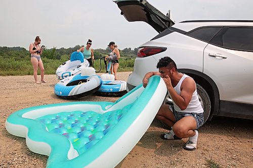 The friends inflate their rafts for floating down the river. (Tim Smith/The Brandon Sun)