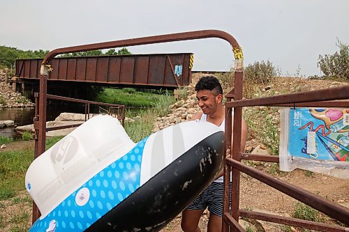 22072024
Luis Alvarenga carries a raft down to the water at Kirkham Bridge west of Brandon for rafting down the Little Saskatchewan River with friends on a hot and humid Monday afternoon. 
(Tim Smith/The Brandon Sun)