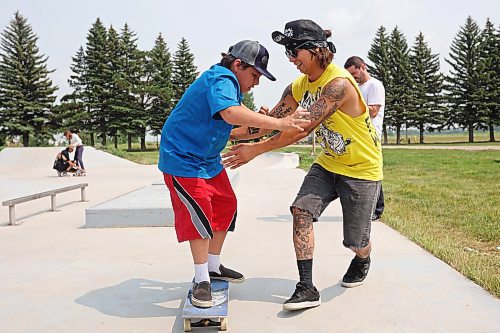 Brendon Sanderson of Winnipeg helps 11-year-old Dom McKay try out skateboarding at the Sioux Valley Dakota Nation skatepark on Tuesday during a skateboarding demo put on by Brandon’s Recovery Skateshop as part of the first day of the inaugural Dakota FACTS Camp. See more photos on Page A3.  (Tim Smith/The Brandon Sun)
