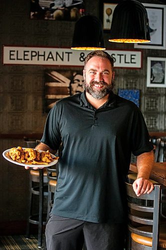 MIKAELA MACKENZIE / FREE PRESS

General manager Dwight Benson holds a plate of chicken fingers at Elephant &amp; Castle on Tuesday, July 23, 2024. 

For Dave Sanderson story.