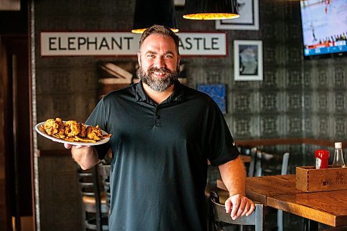 MIKAELA MACKENZIE / FREE PRESS

General manager Dwight Benson holds a plate of chicken fingers at Elephant &amp; Castle on Tuesday, July 23, 2024. 

For Dave Sanderson story.