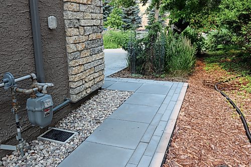 Colleen Zacharias / Free Press
Water from a roof flows into the rain drain situated beneath a downspout where it is diverted into pipes below a sidewalk and absorbed into a mulched swale. 