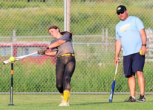 Jessa Church, 13, hits off a tee from centre field under the watchful eye of head coach Greg Beckwith during a fun drill to end a recent U13 Brandon Heat practice. She said her team, which hosts AA provincials this weekend, has been incredibly supportive with each other all season. (Photos by Perry Bergson/The Brandon Sun)
 