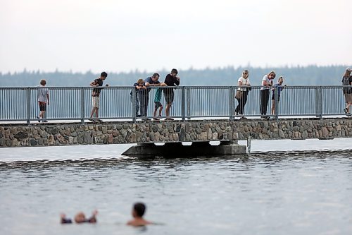 Tourists and vacationers walk the bridge over Clear Lake in Riding Mountain National Park on a warm but overcast Tuesday afternoon in July. (Matt Goerzen/The Brandon Sun)