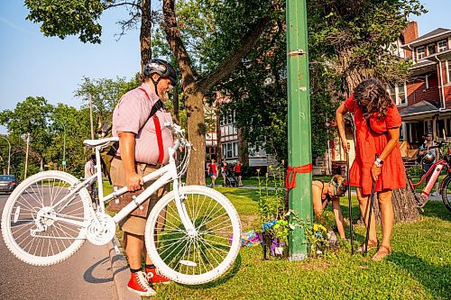 NIC ADAM / FREE PRESS
Winnipeg Bicycle Mayor Patty Wiens (right) helps to set up the memorial ghost bike honouring the life of cyclist Rob Jenner, who lost his life to a hit-and-run driver on Wellington Crescent at Cockburn Street, pictured Thursday afternoon.
240725 - Thursday, July 25, 2024.

Reporter: Jura