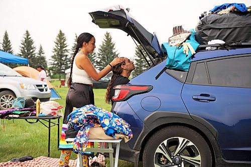 Mikah Whitecloud of Oklahoma helps Tego Warrington of Wisconsin with his hair as Warrington sits in the back of a car while getting ready for Grand Entry. (Tim Smith/The Brandon Sun)