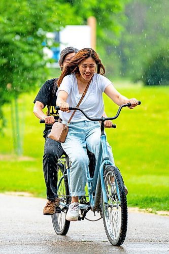 NIC ADAM / FREE PRESS
Carol Sun (front) and Sean Uu get caught in a storm Monday afternoon while riding a tandem bike at Assiniboine Park.
240729 - Monday, July 29, 2024.

Reporter:?