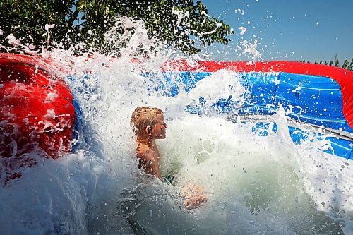 Wacey Anderson is immersed in foamy water while beating the heat on Tuesday on a large inflatable slide at the Andersons' home east of Souris during a birthday party for Kord Anderson, who turns 12 today. (Tim Smith/The Brandon Sun)