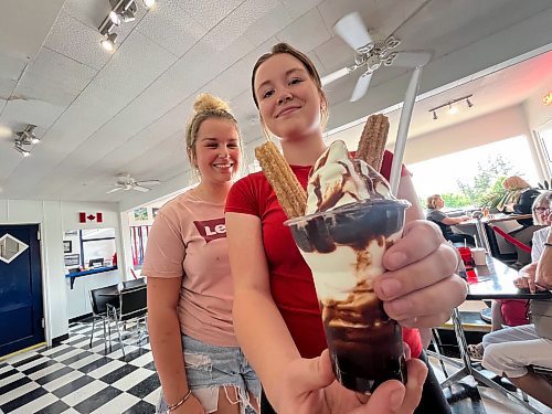 Taylor Jackubowski, left, and Sadie Brown bring out Dari Isle Drive-In's popular churro parfait, which includes two fried and warm churro donuts dipped in cinnamon and sugar, with vanilla soft serve and hot fudge. (Photos by Matt Goerzen/The Brandon Sun)