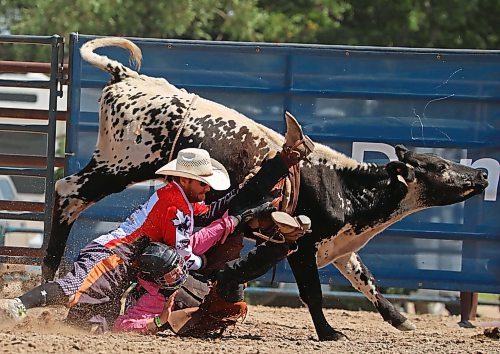 A rodeo protection team member tries to get a tangled Baird away from his steer. (Tim Smith/The Brandon Sun)