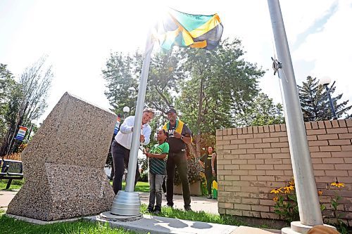 Brandon Mayor Jeff Fawcett and six-year-old Zurik Henlon raise the flag for Jamaica as Emelio Brown, president of the Westman Jamaican Community and secretary-treasurer for the Brandon Chamber of Commerce, looks on during a celebration of the independence day of Jamaica at Brandon City Hall on Tuesday. (Tim Smith/The Brandon Sun)