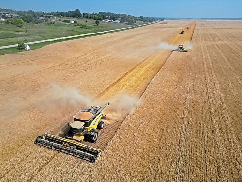 Combines harvest a crop along Grand Valley Road west of Brandon on a smoky Tuesday. (Tim Smith/The Brandon Sun)