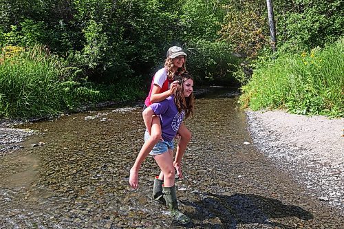 Georgia Richards gives her best friend, Myah LeBoutillier, a piggyback ride across the shale creek at Big Valley northwest of Neepawa after a picnic with Richards' brother and grandmother on Tuesday afternoon. (Tim Smith/The Brandon Sun)