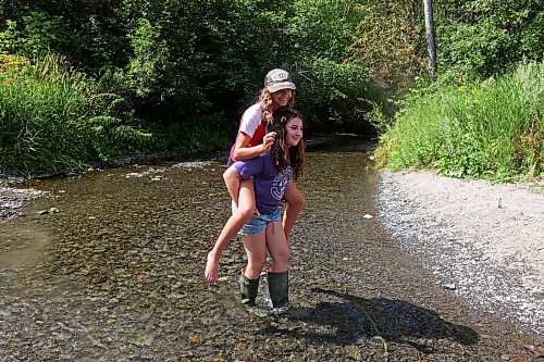 13082023
Georgia Richards gives her best friend Myah LeBoutillier a piggyback ride across the shale creek at Big Valley northwest of Neepawa after a picnic with Richards brother and grandmother on Tuesday afternoon.
(Tim Smith/The Brandon Sun)