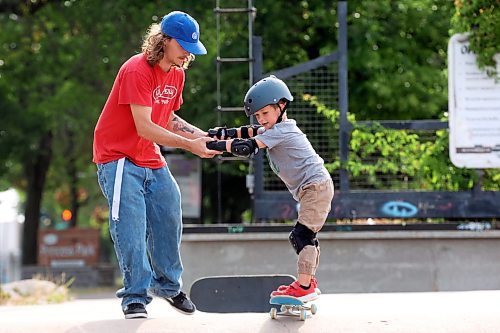 Recovery Skateshop owner Taber Collens helps five-year-old Parker Sigvaldason of Baldur practise rolling down the roll-in. (Tim Smith/The Brandon Sun)