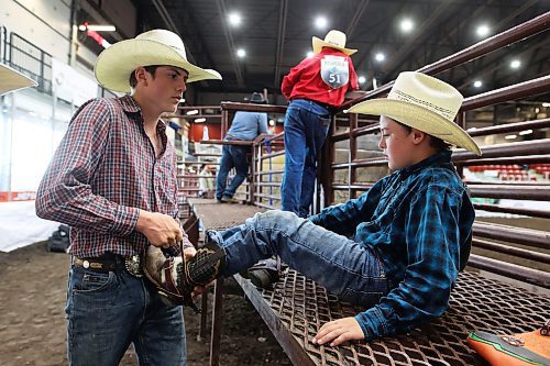 Carter Rosvold helps Lennon Ameel with his boots. (Tim Smith/The Brandon Sun)