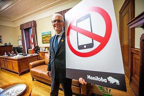 MIKAELA MACKENZIE / FREE PRESS

	
Education minister Nello Altomare shows new school signage (related to the cell phone ban) in his office at the Manitoba Legislative Building on Thursday, Aug. 15, 2024. 

For Carol story.