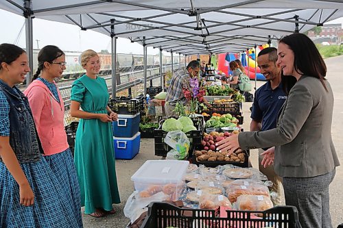 Vendors Heidi Plett (from left), her sister Kaitlyn and Hannah Peters laugh with Westman Immigrant Services executive director Enver Naidoo and Downtown BIZ executive director Emmy Sanderson, as Sanderson tells a joke about doughnut on Friday during the Downtown Summer Market at 1001 Pacific Ave. (Abiola Odutola/The Brandon Sun)