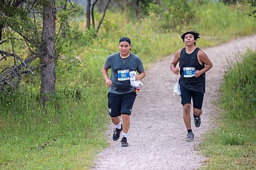 BROOK JONES / FREE PRESS
Fifteen-year-old Phoenix Abraham (left) and 17-year-old Brad Courchene carry Sagkeeng First Nation flags as they compete in the run portion of the Free Spirit Sprint Triathlon in Pinawa, Man., Sunday, Aug. 11, 2024.