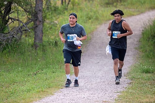 BROOK JONES / FREE PRESS
Fifteen-year-old Phoenix Abraham (left) and 17-year-old Brad Courchene carry Sagkeeng First Nation flags as they compete in the run portion of the Free Spirit Sprint Triathlon in Pinawa, Man., Sunday, Aug. 11, 2024.