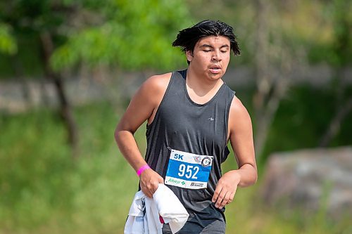 BROOK JONES / FREE PRESS
Seventeen-year-old Brad Courchene carries a Sagkeeng First Nation flag as he competes in the run portion of the Free Spirit Sprint Triathlon in Pinawa, Man., Sunday, Aug. 11, 2024.