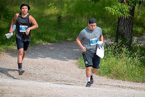 BROOK JONES / FREE PRESS
Seventeen-year-old Brad Courchene (left) and 15-year-old Phoenix Abraham carry Sagkeeng First Nation flags as they compete in the run portion of the Free Spirit Sprint Triathlon in Pinawa, Man., Sunday, Aug. 11, 2024.