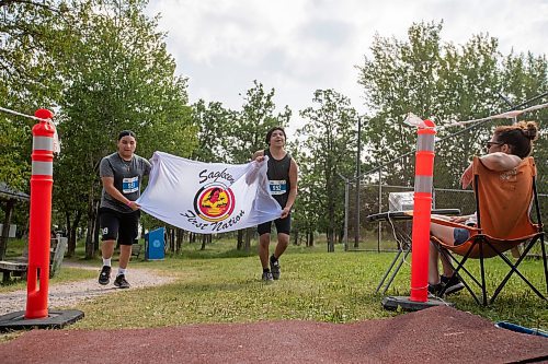 BROOK JONES / FREE PRESS
Fifteen-year-old Phoenix Abraham (left) and 17-year-old Brad Courchene carry a Sagkeeng First Nation flag as they run down the home stretch towards the finish line while competing in the Free Spirit Sprint Triathlon in Pinawa, Man., Sunday, Aug. 11, 2024.