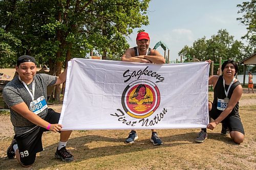 BROOK JONES / FREE PRESS
Jonathan Courchene (middle), who is a First Nations triathlete, 15-year-old Phoenix Abraham (left) and 17-year-old Brad Courchene (right) wear finisher medals around their necks as they hold a Sagkeeng First Nation flag after competing in the Free Spirit Sprint Triathlon in Pinawa, Man., Sunday, Aug. 11, 2024. Courchene has been coaching both youth in the sport of triathlon.