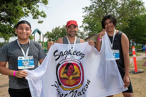 BROOK JONES / FREE PRESS
Jonathan Courchene (middle), who is a First Nations triathlete, 15-year-old Phoenix Abraham (left) and 17-year-old Brad Courchene (right) wear finisher medals around their necks as they hold a Sagkeeng First Nation flag after competing in the Free Spirit Sprint Triathlon in Pinawa, Man., Sunday, Aug. 11, 2024. Courchene has been coaching both youth in the sport of triathlon.