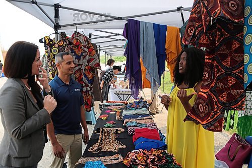 Right: Sumatu Intercontinental Traditional Wears owner Ramatu Suma tells WIS Executive Director Enver Naido and Downtown BIZ Executive Director Emmy Sanderson about her fabrics displayed at the Downtown Summer Market at 1001 Pacific Ave. on Friday. (Abiola Odutola/The Brandon Sun)