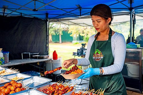 NIC ADAM / FREE PRESS
Nicole Chavez, of K.A Guiao Inihaw Piony Street Foods, serves up a plate of pork bbq to customers at Winnipeg&#x2019;s Streat Feast Festival at the Forks Friday afternoon.
240816 - Friday, August 16, 2024.

Reporter: ?