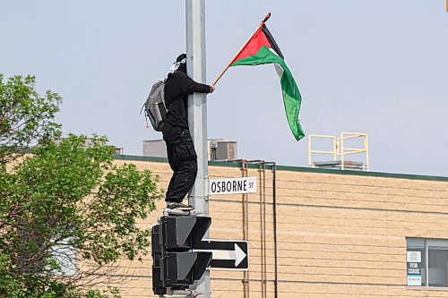 Mike Sudoma/Free Press
A pro-Palestinian protestor waves a Palestinian flag as they stand onto of a crosswalk sign at Confusion Corner Saturday afternoon
August 17, 2024
