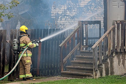 A Brandon Fire and Emergency Services firefighters sprays water on a burning home on First Street on Sunday Afternoon. (Colin Slark/The Brandon Sun)