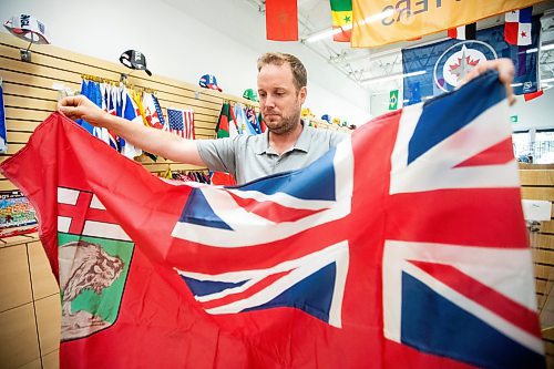 MIKAELA MACKENZIE / WINNIPEG FREE PRESS
	
Mathew Hobson, a sales associate at The Flag Shop on Osborne, shows the current Manitoba flag on Monday, Aug. 19, 2024. According to a Probe Research poll, 49% of Manitobans would support creating a new flag for the province.

Winnipeg Free Press 2024