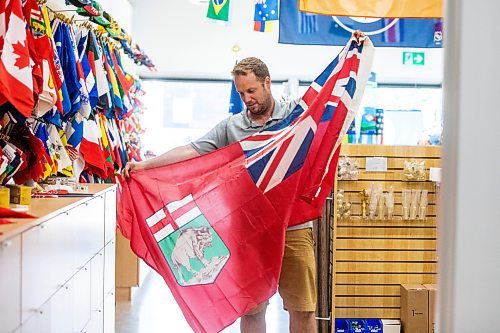 MIKAELA MACKENZIE / WINNIPEG FREE PRESS
	
Mathew Hobson, a sales associate at The Flag Shop on Osborne, shows the current Manitoba flag on Monday, Aug. 19, 2024. According to a Probe Research poll, 49% of Manitobans would support creating a new flag for the province.

Winnipeg Free Press 2024